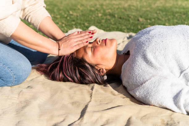 Latin woman in reiki session with other woman lying on a park